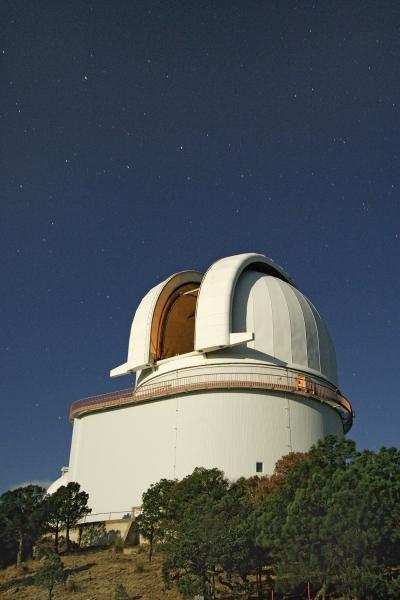 Stars shine in an inky night sky above the open dome of the Harlan J. Smith Tele