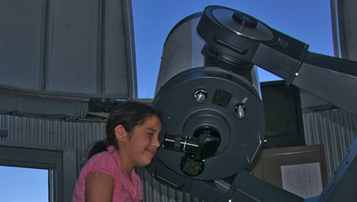 Girl looking through telescope during lunar viewing.