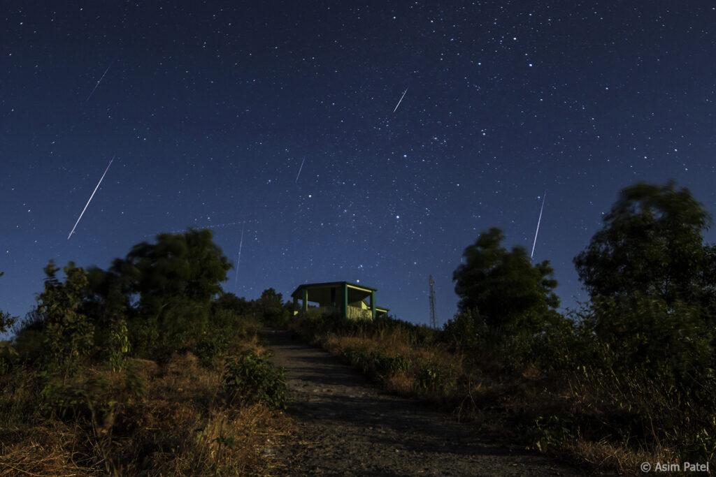 Meteors flying over a small building.