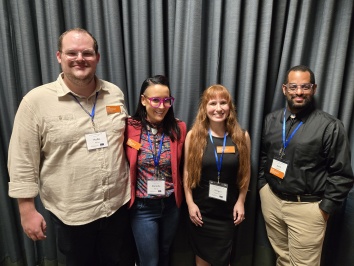 Four people standing in front of a curtain.