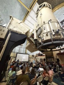Crowd seated inside a large telescope.