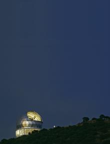 The Hobby-Eberly Telescope gleams in silver and gold against a deep blue night s