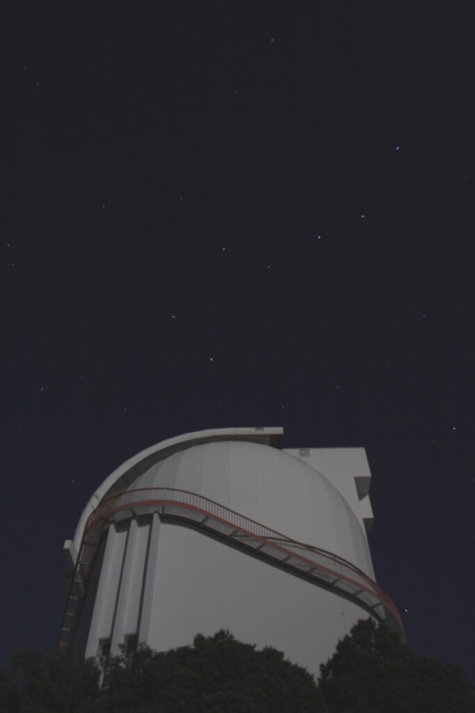 Photo of a telescope, taken at night.